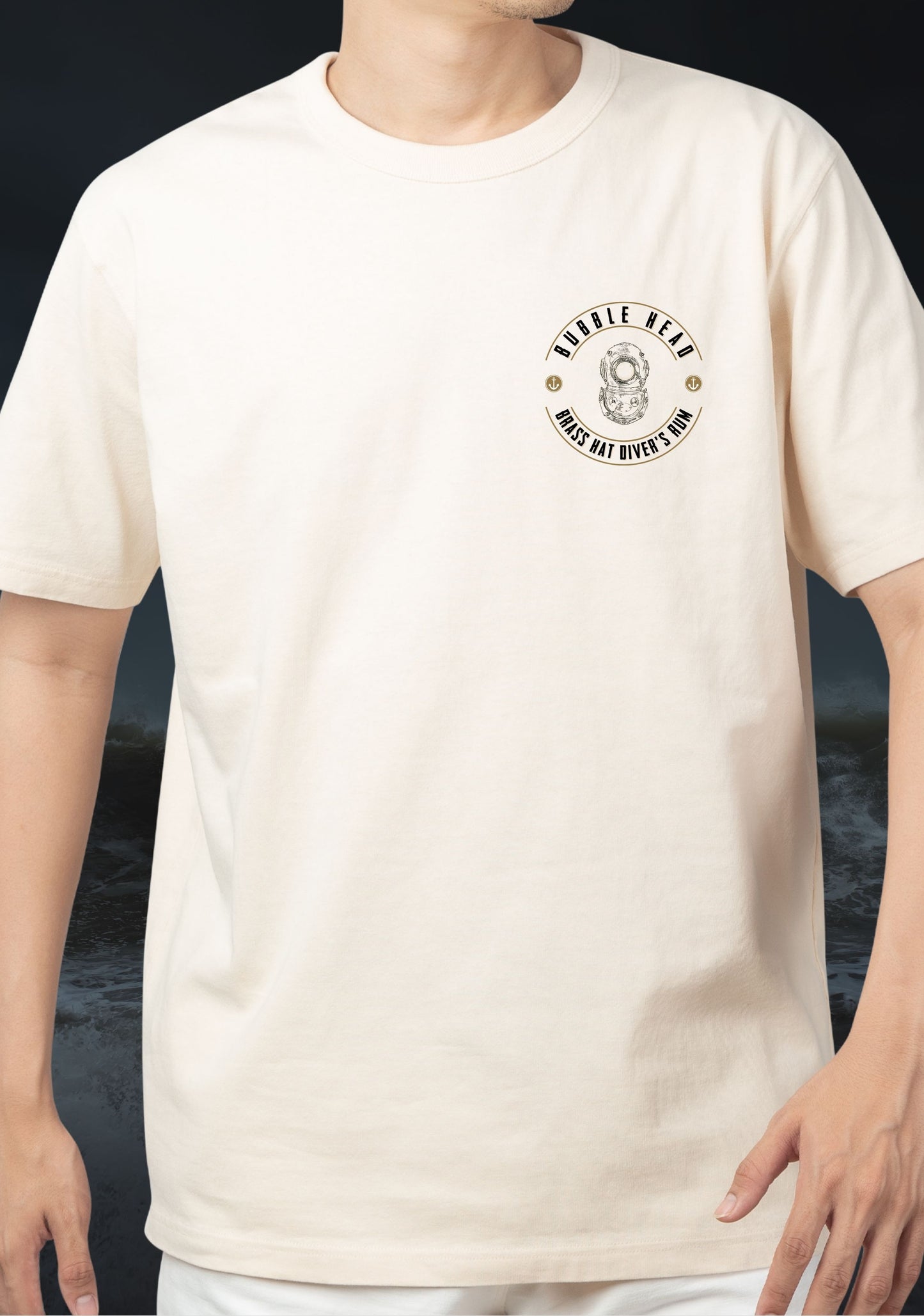 Person wearing a beige t-shirt with a logo which states 'Bubble Head' and "Brass Hat Diver's Rum' in text and a graphic of a Siebe Gorman Diver's Helmet, all set against a dark stormy seascape background