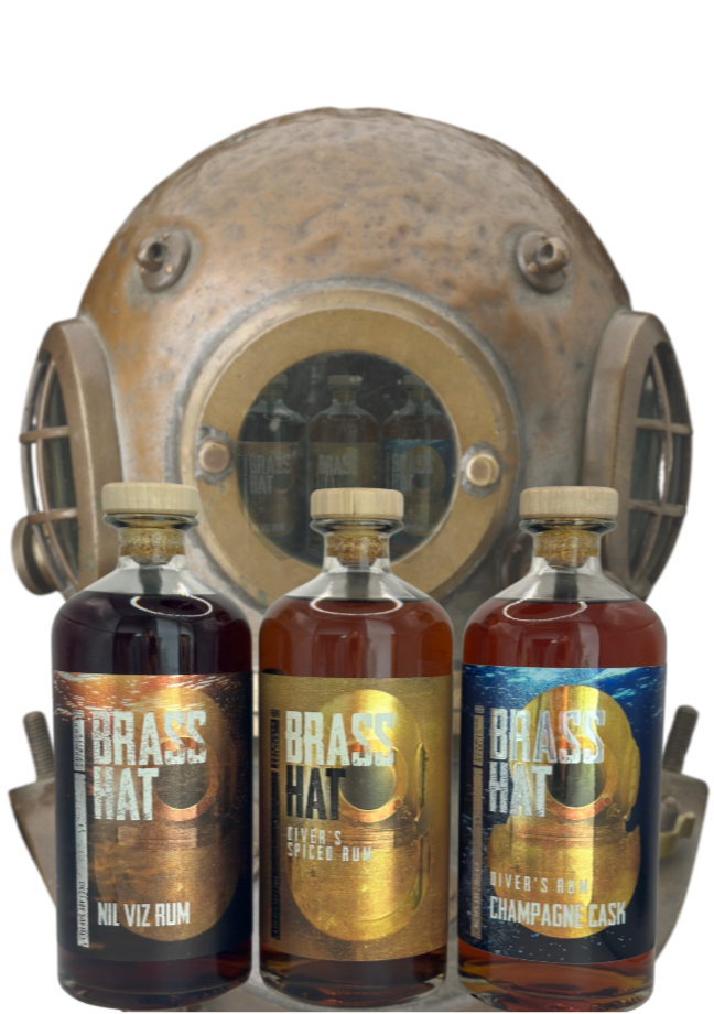Three bottles of Brass Hat rum in front of a vintage diving helmet on a white background