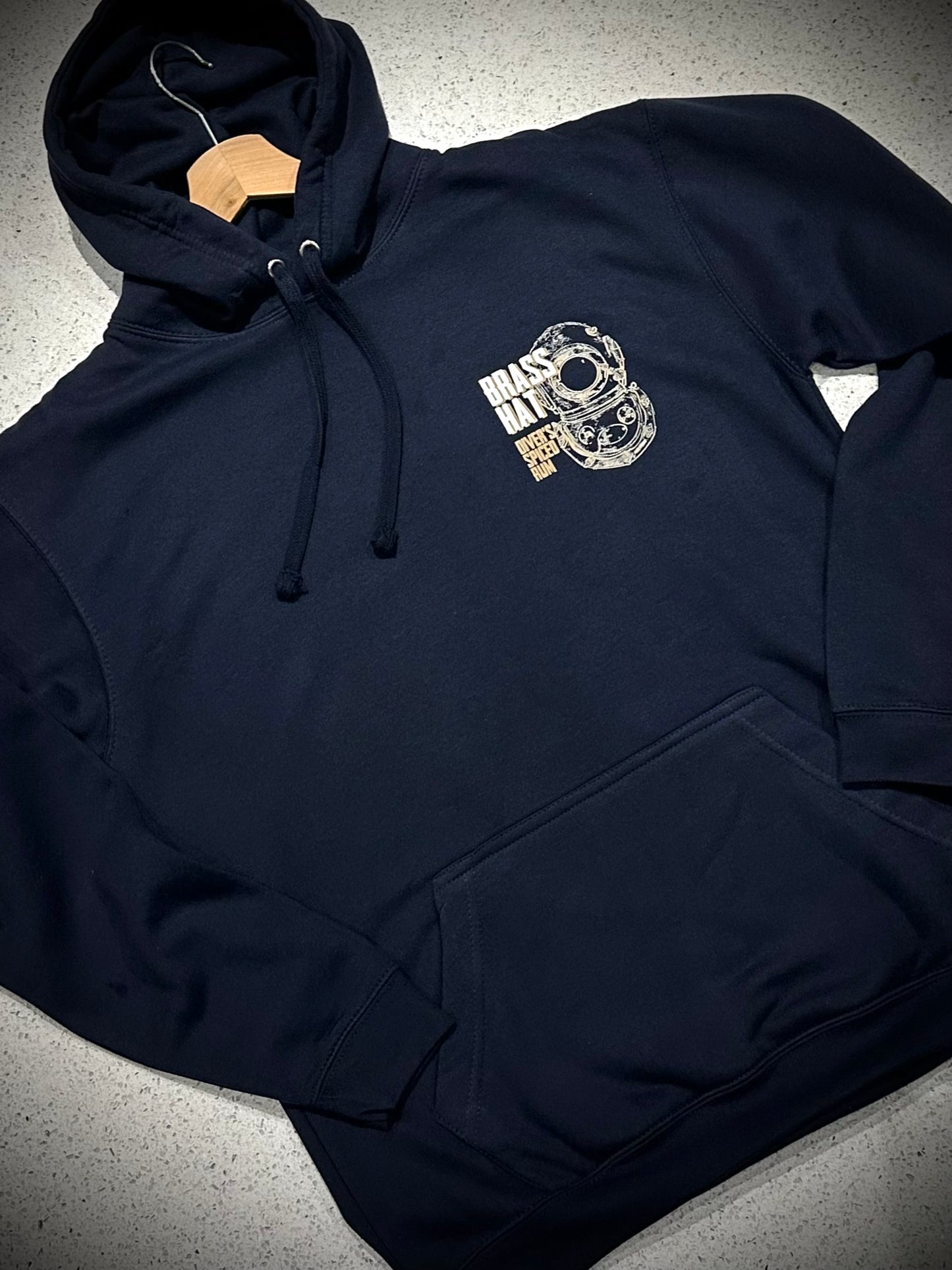 Front view of a navy blue hoodie with diving helmet logo and Brass Hat Diver's Spiced Rum name front pocket and hood strings
