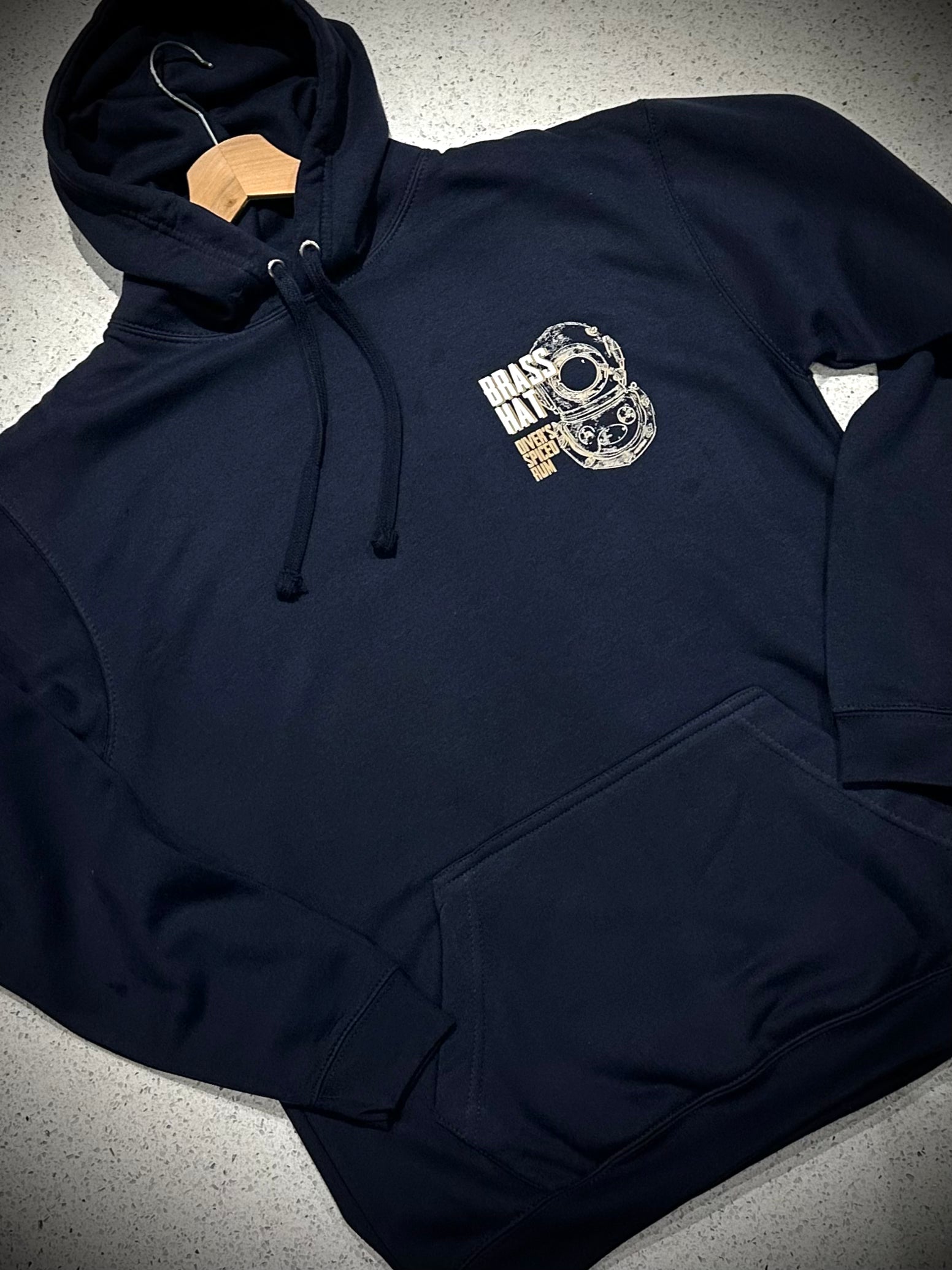 Front view of a navy blue hoodie with diving helmet logo and Brass Hat Diver's Spiced Rum name front pocket and hood strings