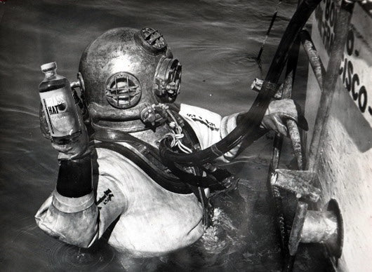 Vintage diver surfacing holding a bottle of Brass Hat Rum – divers’ gifts inspiration