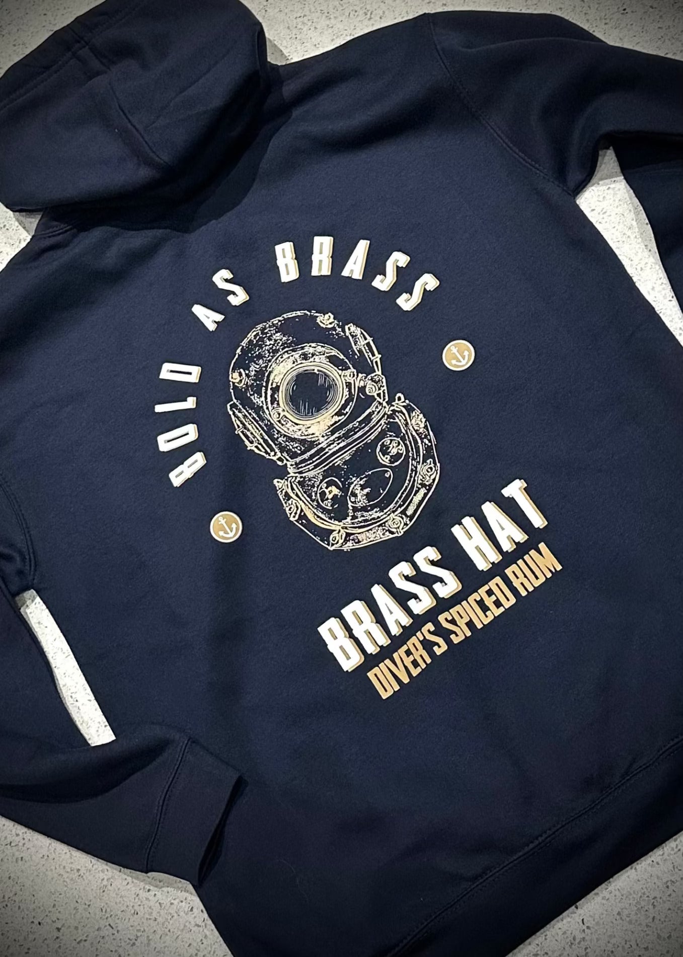ack view of Brass Hat navy blue hoodie with ‘Bold as Brass’ text, diving helmet logo, anchor motifs – divers’ gifts and ocean-inspired apparel