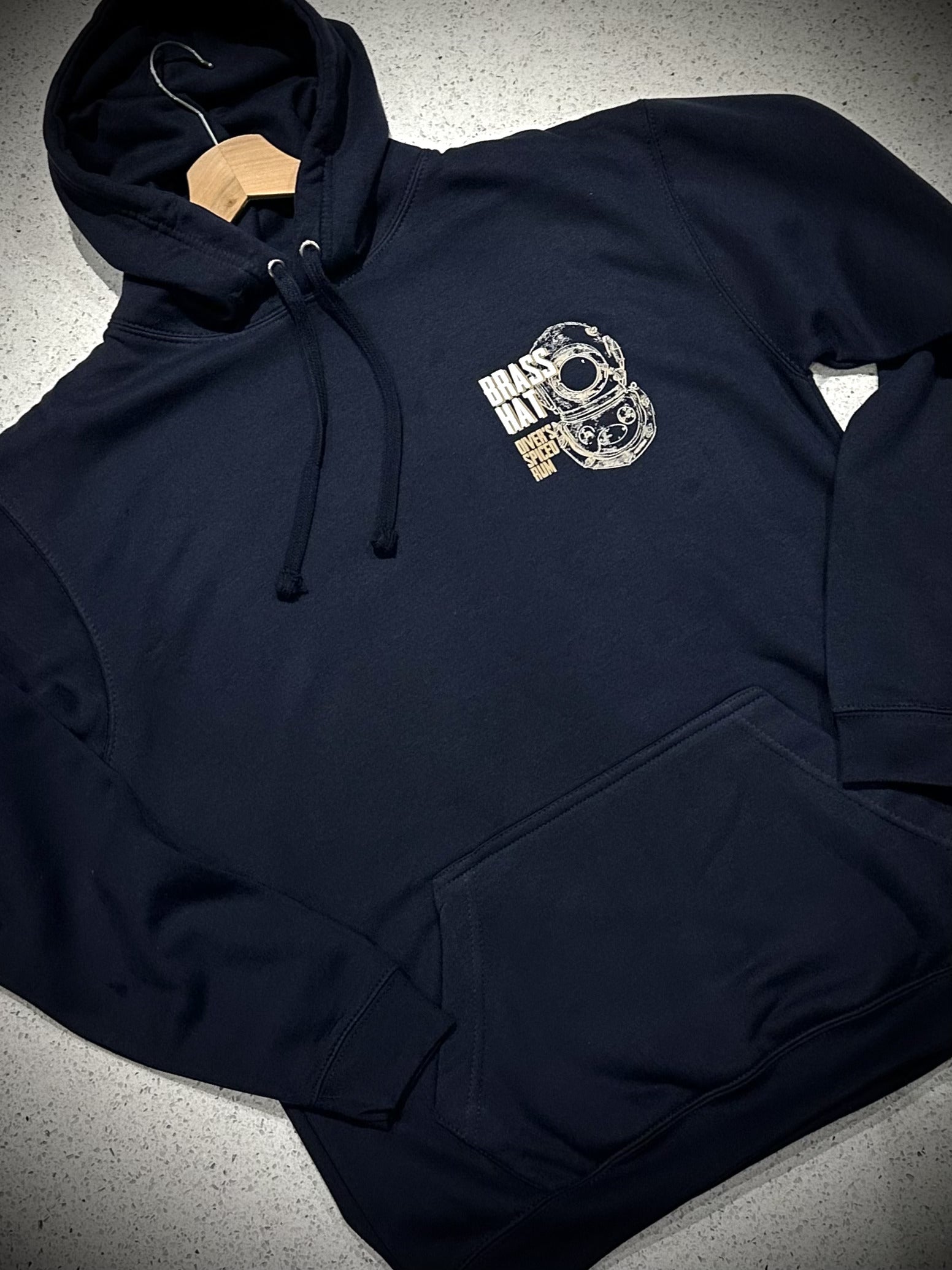 Front view of Brass Hat Diver’s Spiced Rum navy blue ‘Bold As Brass’ hoodie. Small diving helmet logo and brand name to front left chest– divers’ gifts and ocean-inspired apparel