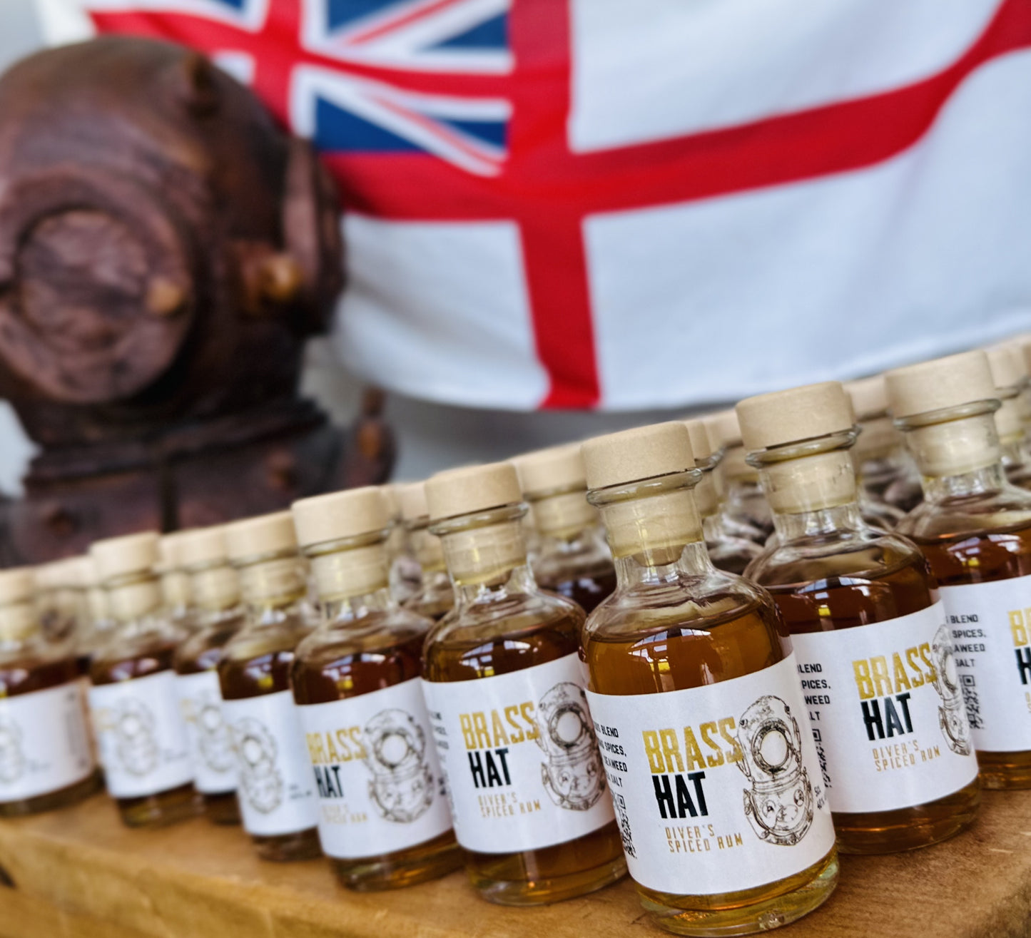 Miniature bottles of Brass Hat Diver’s Rum arranged as table favours with a vintage diving helmet and Union Jack flag, perfect for divers’ military reunion gifts or event favours