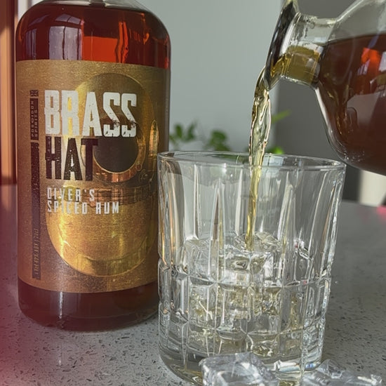 slow motion video of a bottle of Brass Hat Diver's Spiced Rum being poured into a crystal glass with ice cubes
