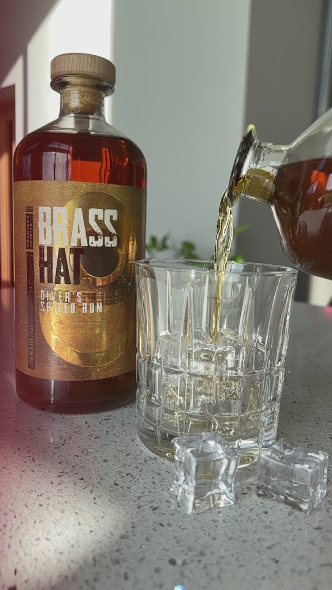 slow motion video of a bottle of Brass Hat Diver's Spiced Rum being poured into a crystal glass with ice cubes